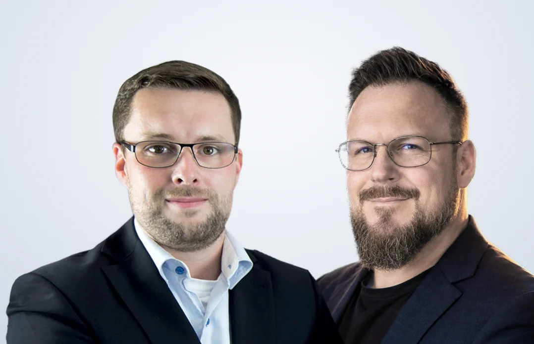 Kay Göthling (links) und Andreas Ehrlich (rechts) im Sakko vor hellem Grund