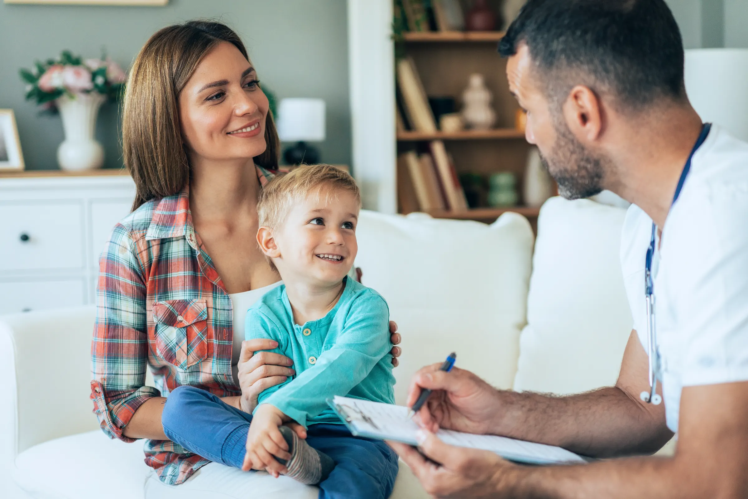 Mutter mit kleinem Sohn im Gespräch mit einem Arzt, der Notizen macht