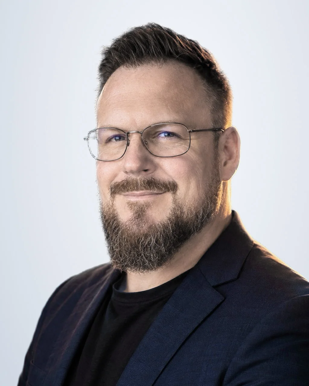 Andreas Ehrlich, Versicherungsmakler der POLICEN Werkstatt in Erfurt, im dunkelblauen Sakko vor hellem Grund